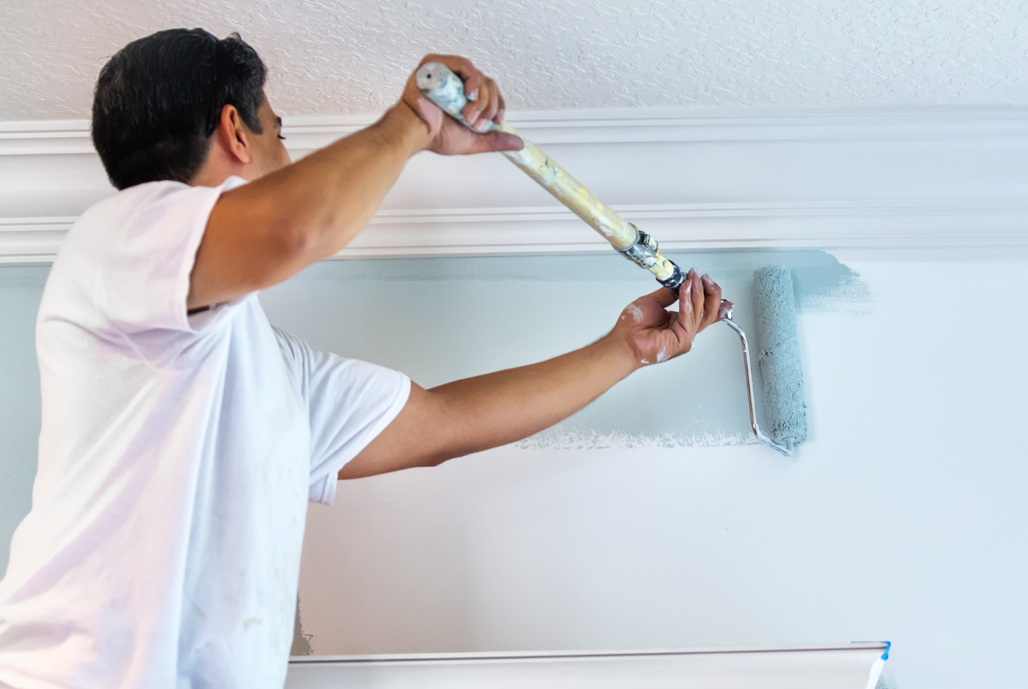 Person painting a ceiling with a roller