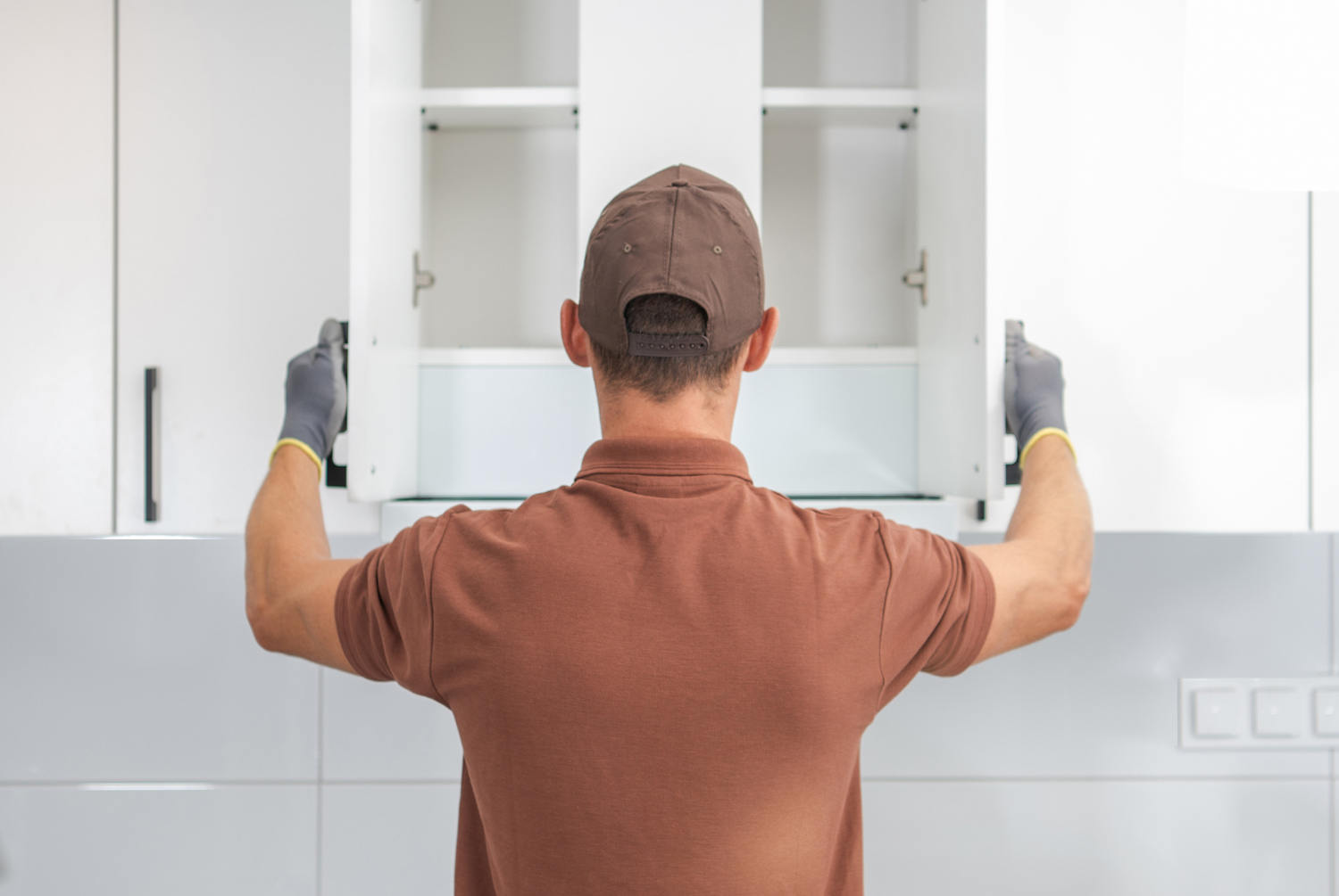Person installing kitchen cabinets in a modern kitchen.