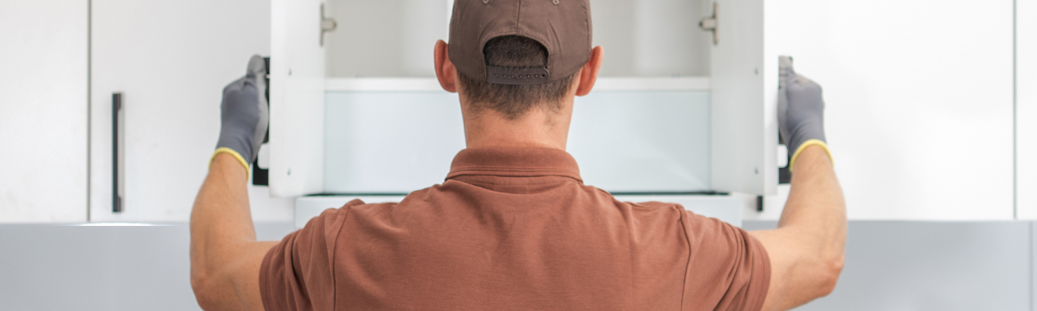 Person installing kitchen cabinets in a modern kitchen.