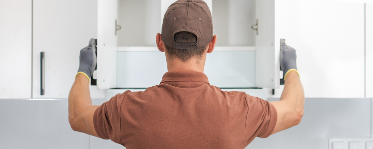 Person installing kitchen cabinets in a modern kitchen.
